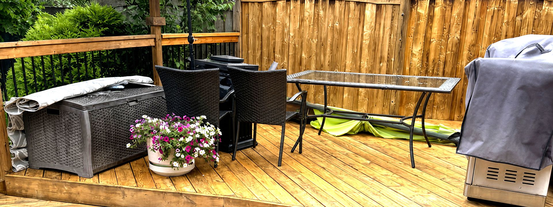 Newly stained cedar deck with patio furniture, umbrella and board fence