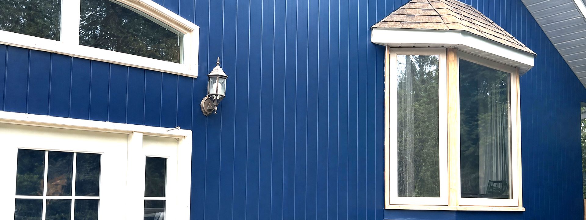 Exterior repaint in deep navy board-and-batten siding with crisp white door and window trim