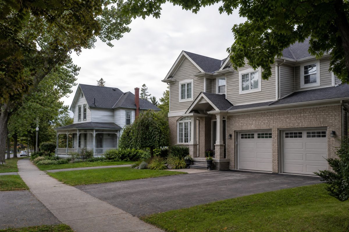 Barrie residential street showing a newer subdivision home beside an older century home with painted wood siding