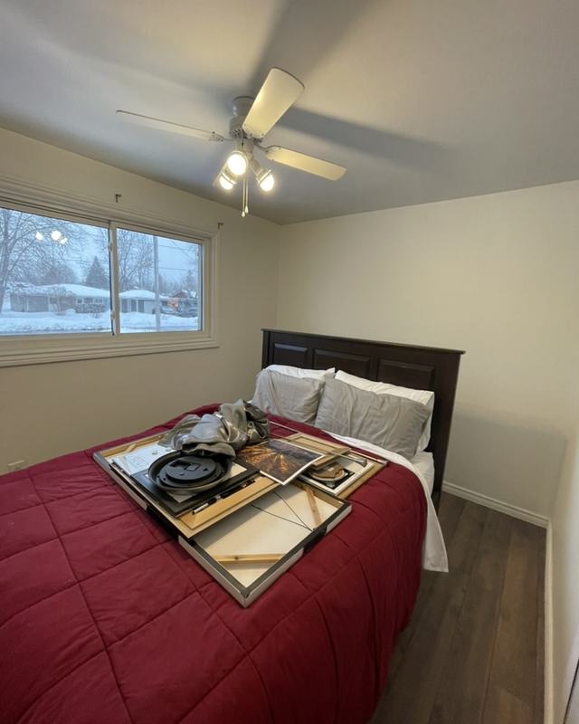 Repainted bedroom with smooth neutral walls, white ceiling and trim, bed made up in red bedding
