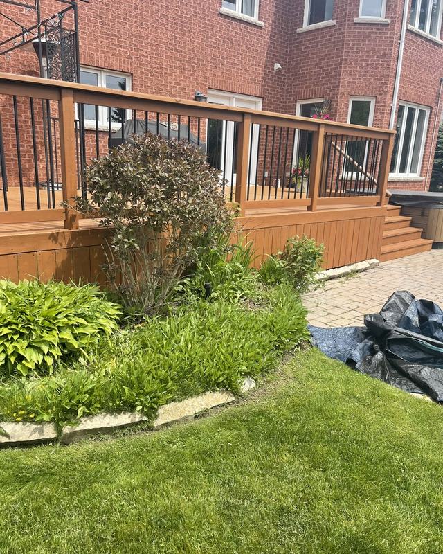 Cedar-stained deck with matching stairs and skirting on a brick home, perennial garden and paver patio alongside