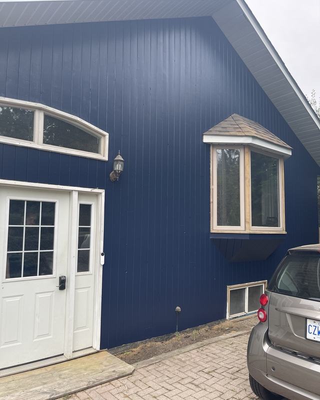 Front of a home painted deep navy with crisp white trim, bay window and white entry door