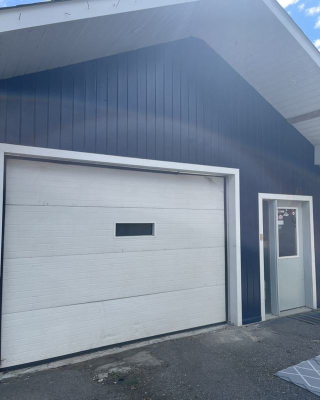 Detached garage painted deep navy with a white overhead door and white side entry door