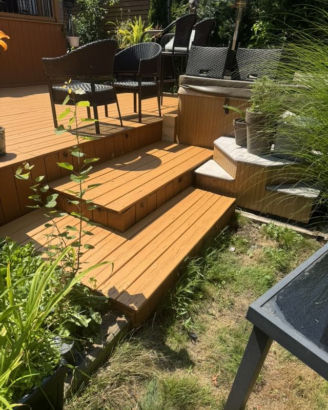 Multi-level stained deck with wide steps down to a garden, patio dining set and armour stone edging
