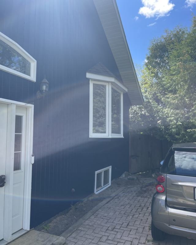 Driveway elevation of a home painted deep navy with white entry door, arched window and paver drive
