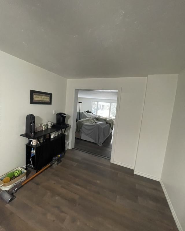 Hallway after painting looking through to a bedroom, white walls and trim over dark plank flooring
